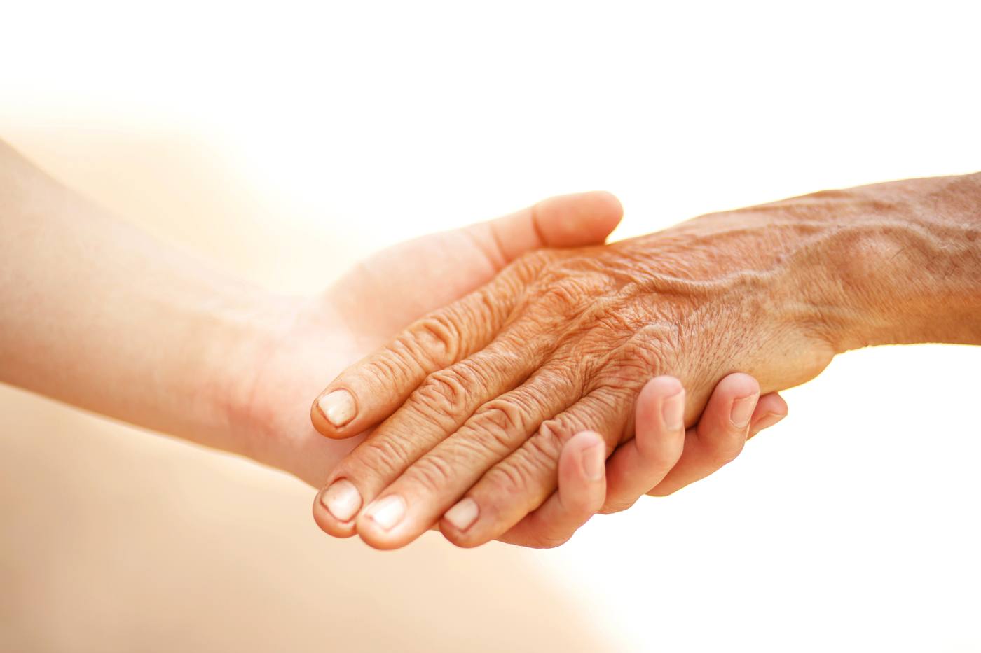 A carer holding the hand of an older person